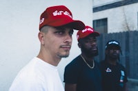 three men standing next to each other wearing red hats